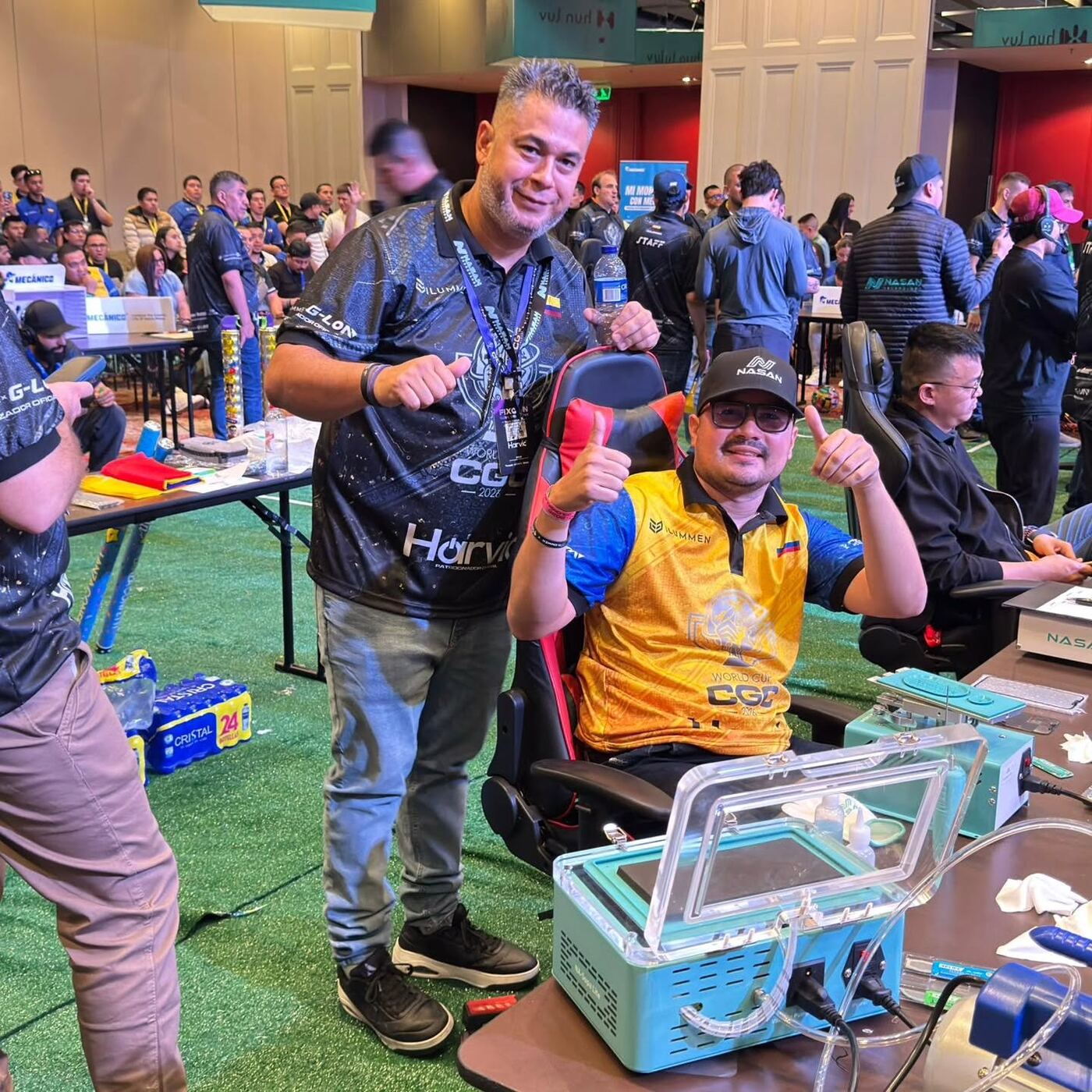 Técnicos venezolanos compitiendo en el CGC World Cup, en un salón lleno de puestos de reparación